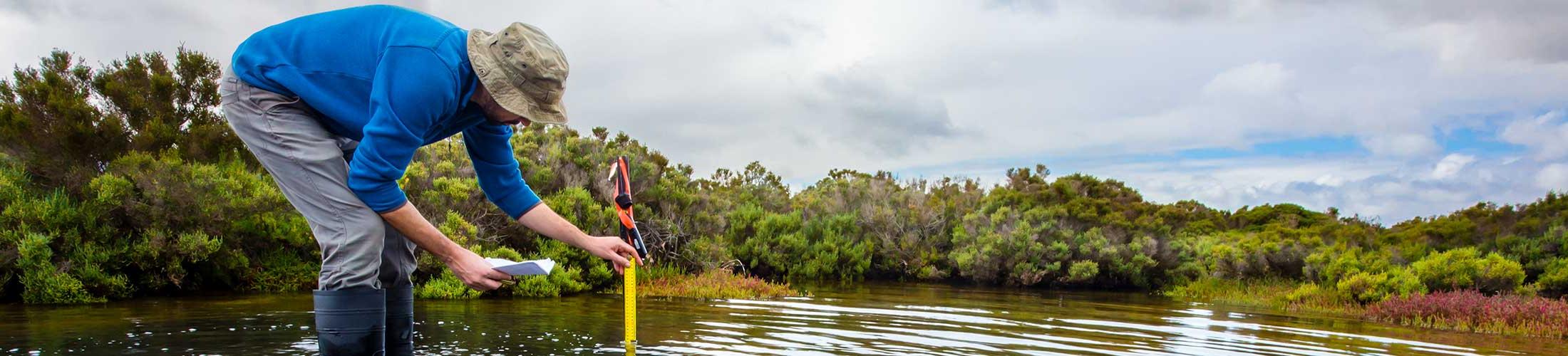 Man with measuring stick in water.